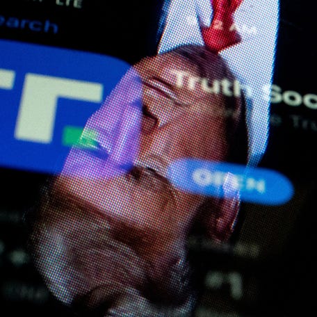 This photo illustration shows an image of former President Donald Trump reflected in a phone screen that is displaying the Truth Social app.