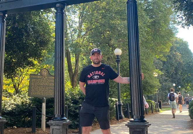 Chris Biggs stands at the iconic UGA Arch on the corner of the campus and downtown Athens.