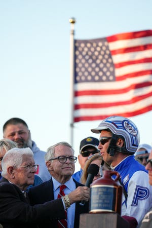 Sep 22, 2022; Delaware, Ohio, USA; Chris Page, right, speaks with race officials and Ohio Gov. Mike DeWine after his win of the 77th Little Brown Jug harness race on Thursday at Delaware County Fairgrounds. Mandatory Credit: Joseph Scheller-The Columbus Dispatch