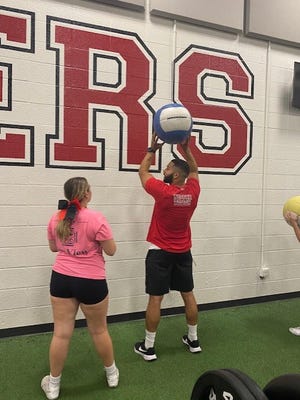 Durfee strength and conditioning coach Cabrinni Goncalves helps a student athlete during a workout session.