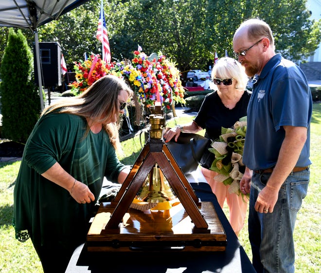 Sep 23, 2022; Brookwood, AL, USA; Crystal Davis, Alvin Davis and Saundie Smith set up a memorial bell as coal miners and family members mark the 21st Anniversary of the mine explosion at the Jim Walter Resources Mine No. 5 in Brookwood that claimed 13 lives on Sept. 23, 2001.