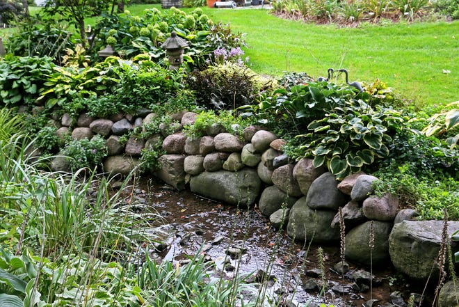 Perennials and annuals accent the area where Judy Schmidt added boulders to enhance a ditch and reduce erosion at her Franklin home.