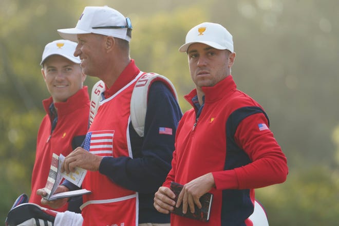 Jordan Spieth, left, caddie Jim Mackay, center, and Justin Thomas stand on the fifth green for Team USA during foursomes play at the 2022 Presidents Cup.