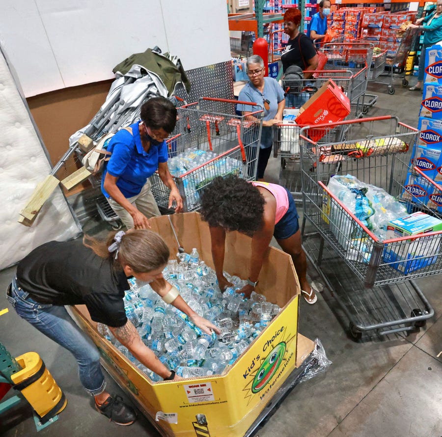 Shoppers at the Costco store in Altamonte Springs, Fla. grab bottles of water from the last pallet in stock on Monday, Sept. 26, 2022, as Central Floridians prepare for the impact of Hurricane Ian.