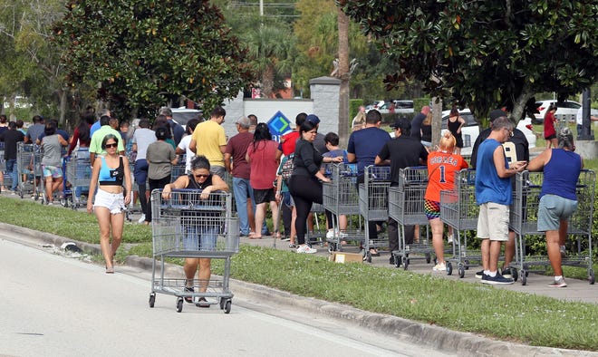 Shoppers walk to join a line stretching beyond the parking lot outside a retail warehouse as people rush to prepare for Hurricane Ian, in Kissimmee, Florida, on September 25, 2022.