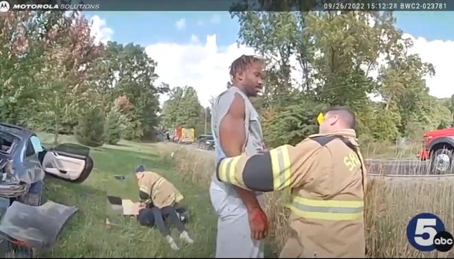 In this screenshot of a video released by the Medina County Sheriff's Office, a firefighter helps Myles Garrett to his feet after Garrett crashed his car in Medina County. In the background, his passenger is being treated by a first responder. Her face had been edited out of the footage.