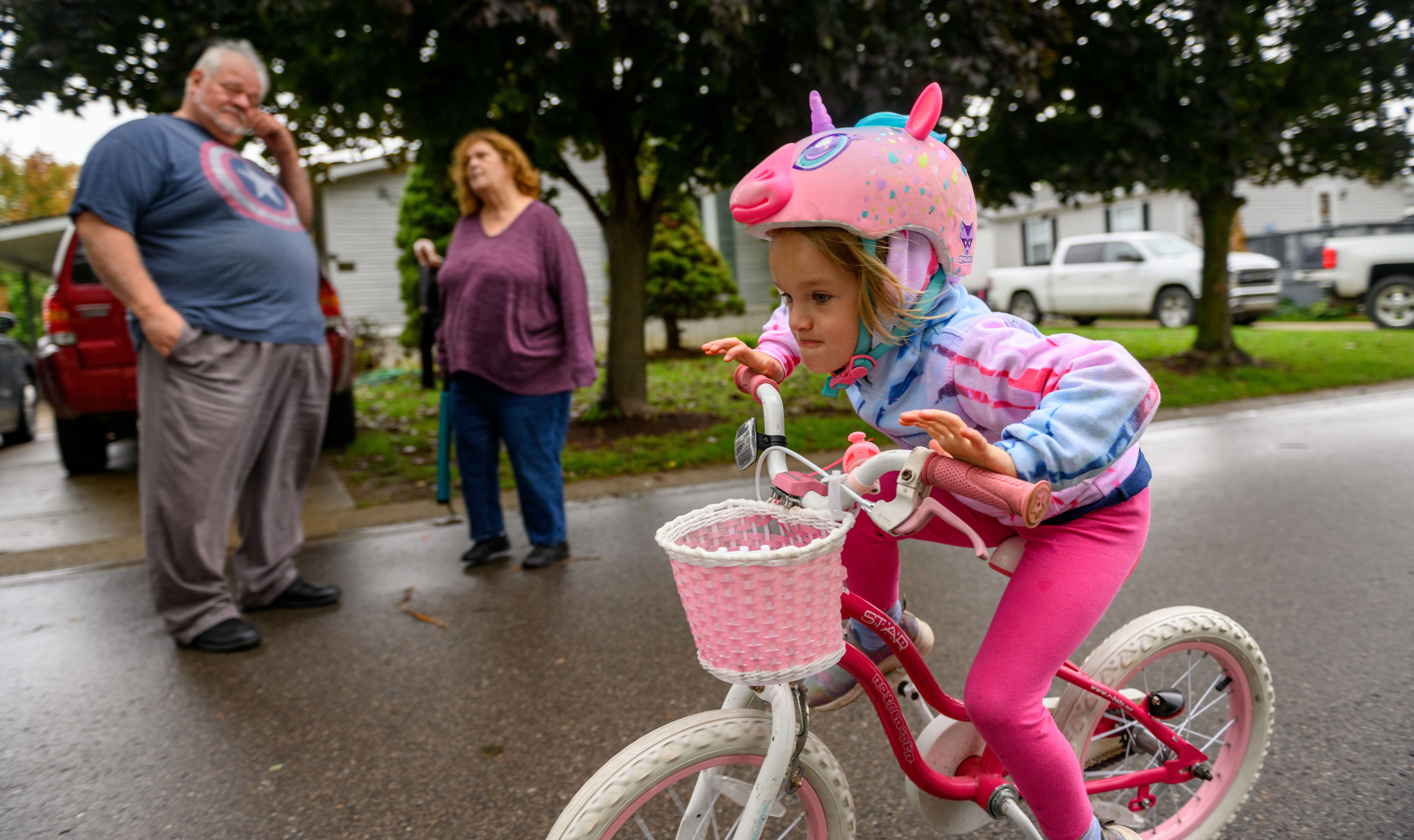 Ken Firth and his wife, Sue, watch their six-year-old granddaughter, Aurora Hendry, ride her bike at their home in White Lake Township.