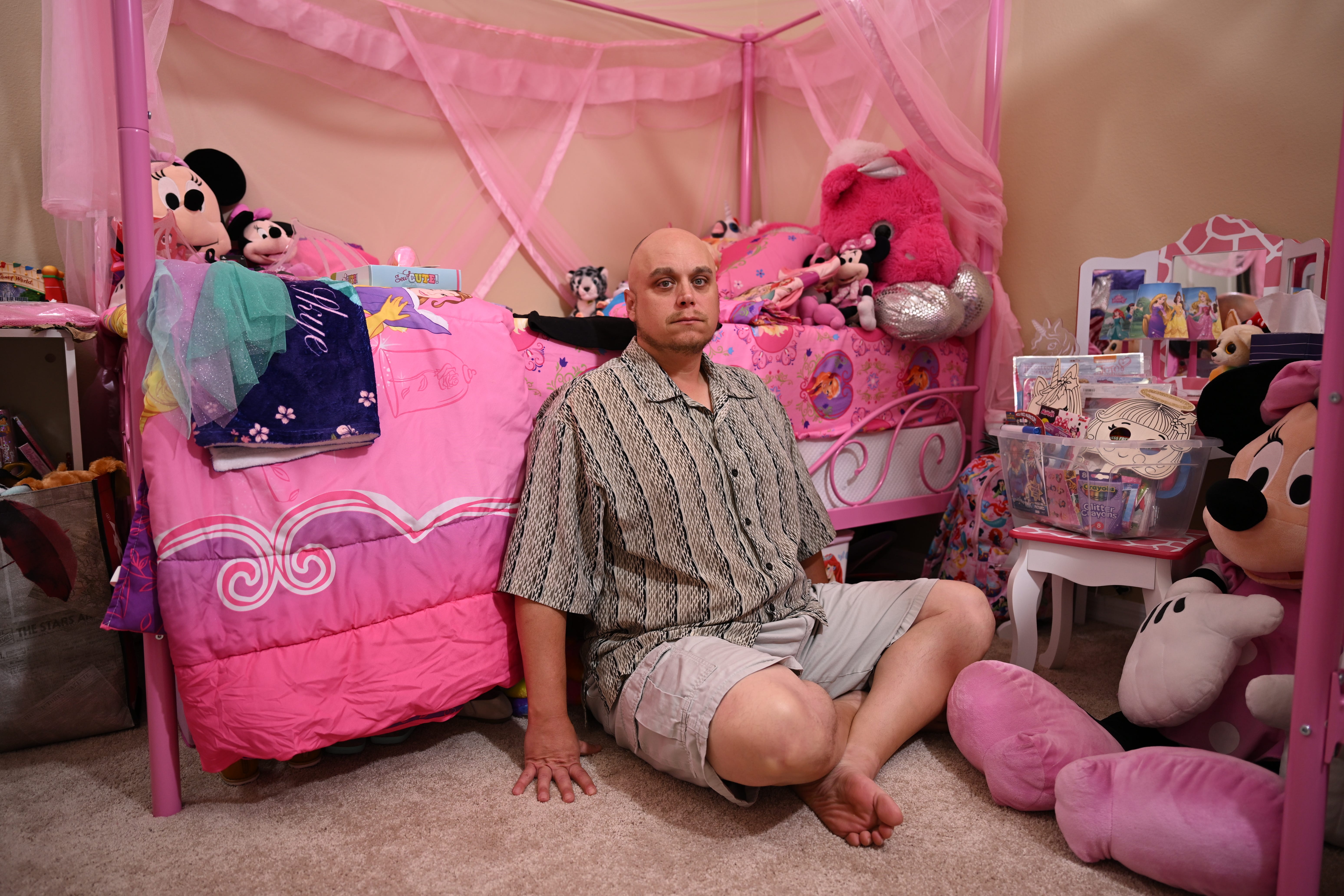 John Rex sits in his missing daughters' bedroom, which is very pink and Minnie Mouse-themed.