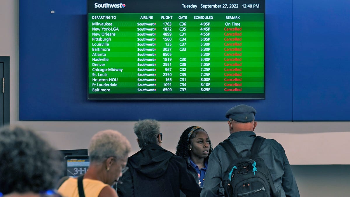 Southwest Airline passengers check into a ticket counter near a sign that shows canceled flights at the Tampa International Airport Tuesday, Sept. 27, 2022, in Tampa, Fla. The airport is closing at 5 pm EST ahead of Hurricane Ian.