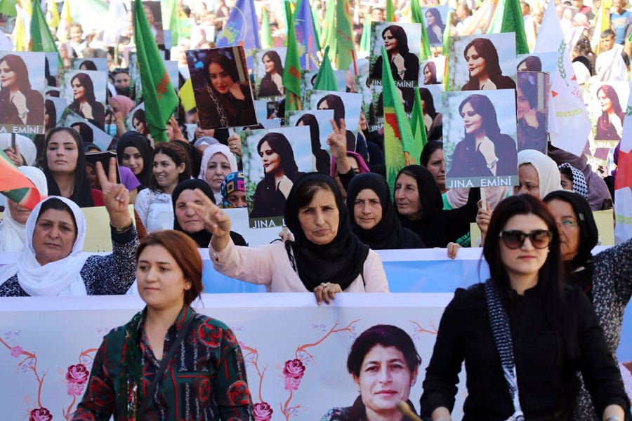 In this photo provided by Kurdish-run Hawar News Agency, Kurdish women hold portraits of Iranian Mahsa Amini during a protest condemning her death in Iran, in the city of Qamishli, northern Syria, Monday, Sept. 26, 2022. Protests have erupted across Iran in recent days after Amini, a 22-year-old woman, died while being held by the Iranian morality police for violating the country's strictly enforced Islamic dress code.