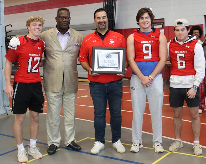 Milton High football coach Steve Dembowski poses with former New England Patriot linebacker Andre Tippett, now the team’s Executive Director of Community Affairs, after being selected as the New England Patriots High School Coach of the Week. Also shown are Milton players Owen McHugh (No. 12), K.J. Beckett (No. 9) and Jack Finnegan (No. 6).