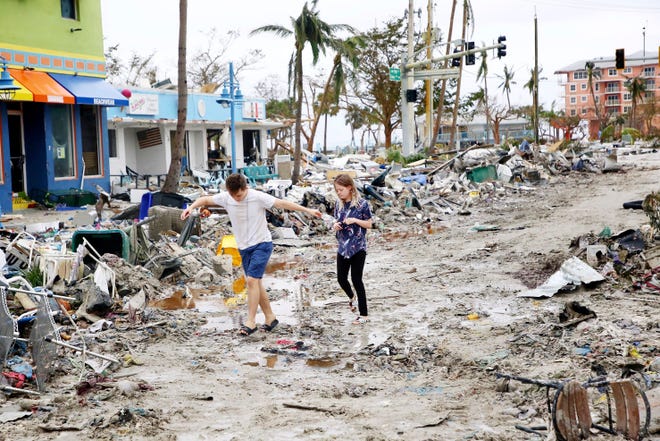 Jake Moses, 19, left, and Heather Jones, 18, of Fort Myers, explore a section of destroyed businesses at Fort Myers Beach, Florida, on Thursday, Sept. 29, 2022, following Hurricane Ian.