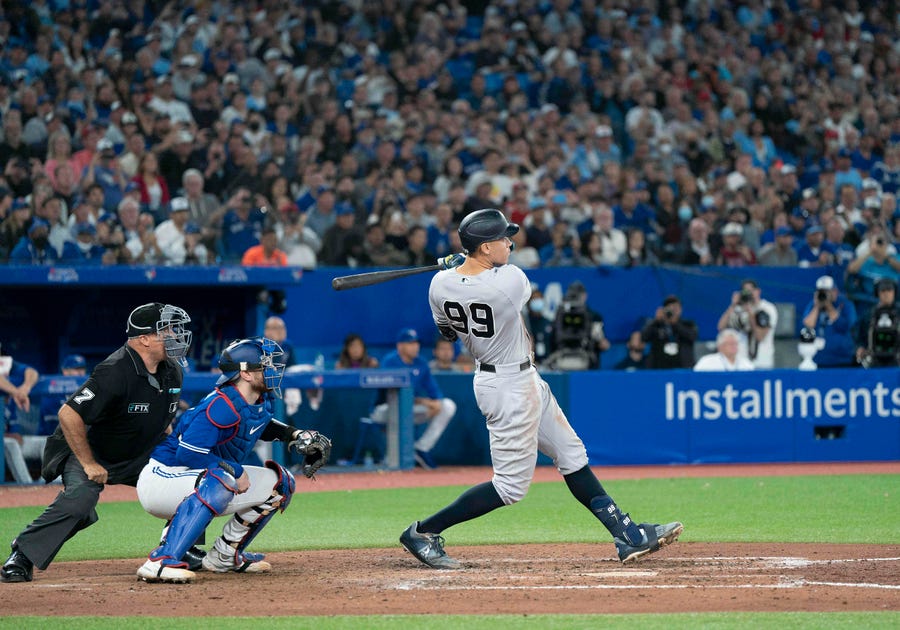 New York Yankees designated hitter Aaron Judge (99) hits his 61st home run scoring two runs against the Toronto Blue Jays during the seventh inning at Rogers Centre. 