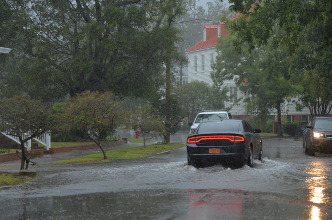 Cars drive through a flooded area along East Front Street in New Bern Friday morning.