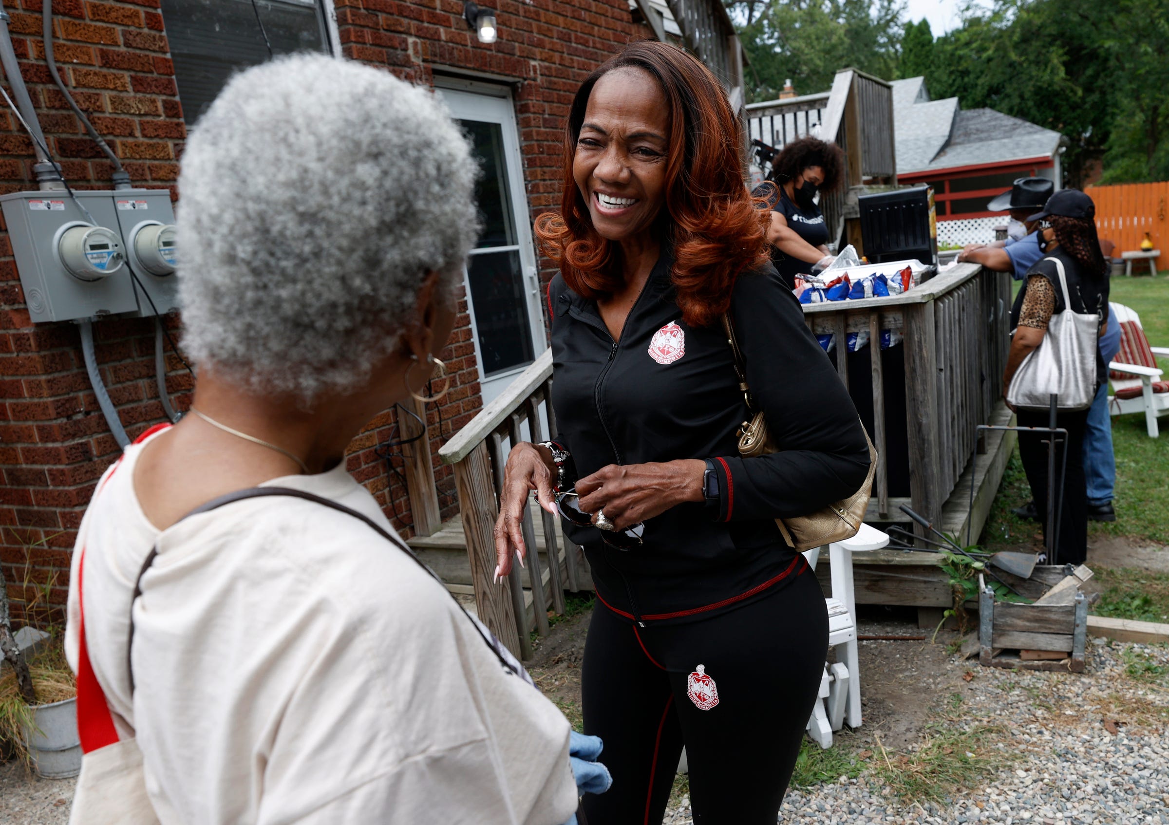 Earlene Hall, right, talks with one of many people in line on Tuesday, Sept. 20, 2022, during SDM2 Projection Education's weekly food giveaway in Detroit. Hall is retired is still very active in community organizations like SDM2 Project Education.