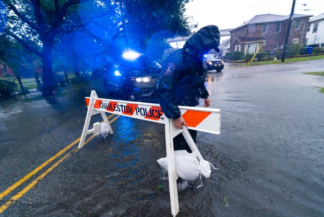 A Charleston police officer moves a barricade to block a flooded street as the effects from Hurricane Ian are felt, Friday, Sept. 30, 2022, in Charleston, South Carolina.