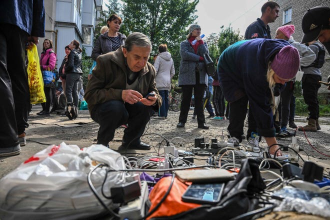 Residents charge their mobile phones outside a humanitarian centre in Izyum, eastern Ukraine, on 29 September 2022, amid the Russian invasion of Ukraine.