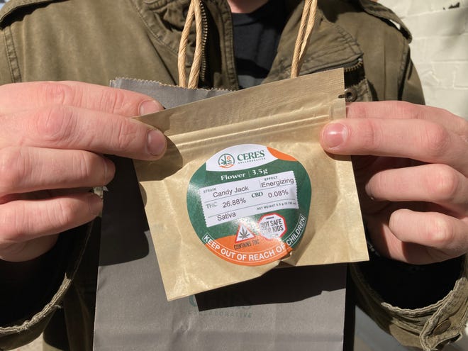Brandon Coburn of St. Albans holds his purchase - an eighth of an ounce of cannabis flower - Oct. 1, 2022 near the Ceres Collaborative store in Burlington on the first day of retail adult-use cannabis sales in Vermont.
