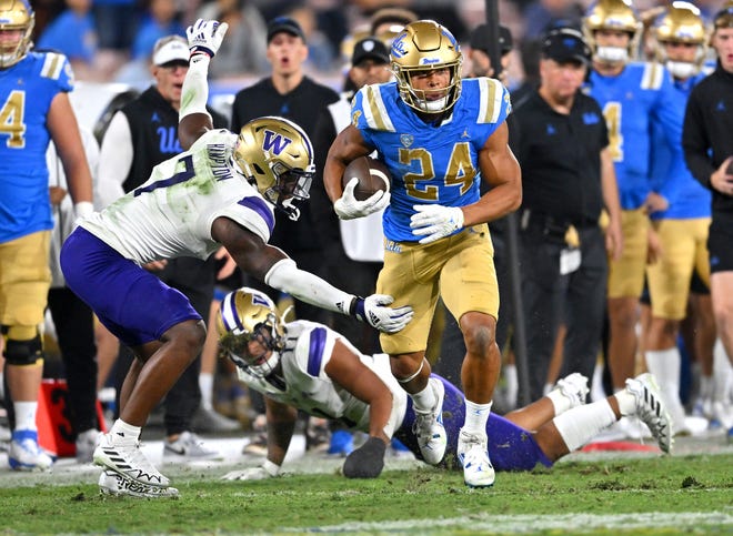 UCLA running back Zach Charbonnet gets past Washington linebacker Dominique Hampton for a first down in the first half at the Rose Bowl.