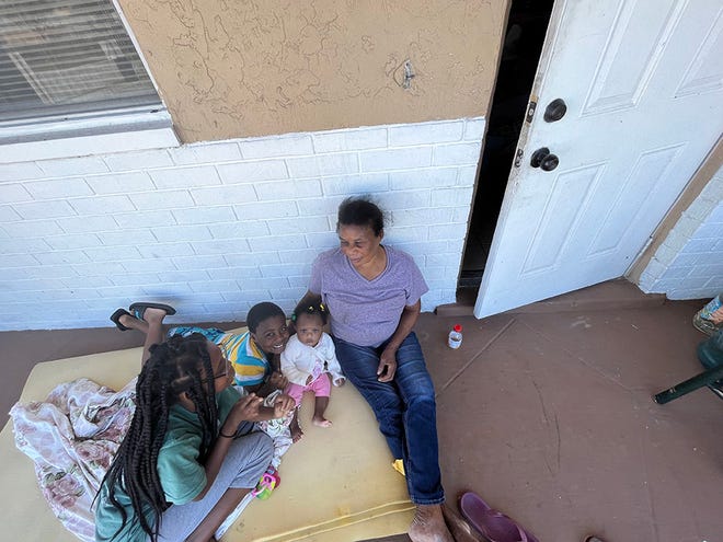 Fort Myers resident Marie Fleurette Radius and her grandchildren cool off outside after the power remains out following Hurricane Ian on Sept. 30, 2022.