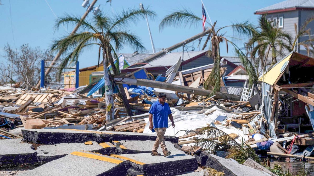 A man walks over a broken section of the Pine Island Road in the aftermath of Hurricane Ian in Matlacha, Florida on October 1, 2022. - Shocked Florida communities counted their dead October 1, 2022, as the full scale of the devastation came into focus, two days after Hurricane Ian tore into the coastline as one of the most powerful storms ever to hit the United States.