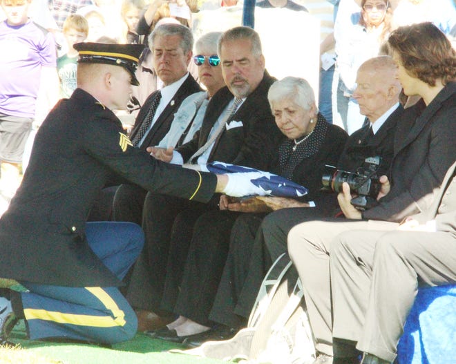 A sergeant of the Honor Guard from Ft. Leonard Wood presents the American flag to Merle Ferguson. The flag had draped the coffin that carried the remains of Pfc. John L. Ferguson, an older brother of Merle Ferguson who died Dec.10, 1942, in the Philippines. Pfc. Ferguson was laid to rest Saturday, Oct. 1, at Gridley Cemetery.