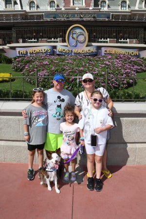Nina Byrd and her family visit Walt Disney World's Magic Kingdom with service dog Kona. Kona's paws are covered in balm for extra protection in the park.