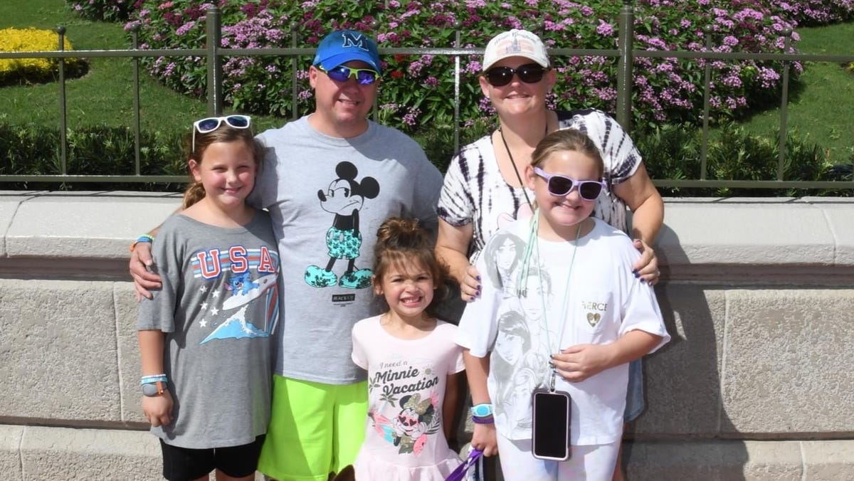 Nina Byrd and her family visit Walt Disney World's Magic Kingdom with service dog Kona. Kona's paws are covered in balm for extra protection in the park.