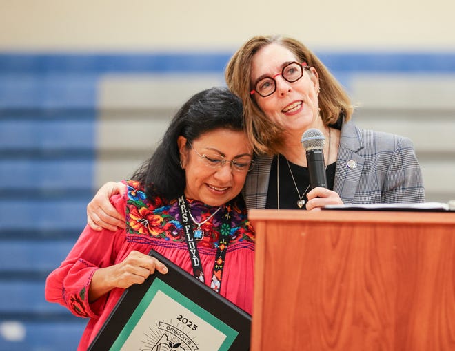 Gov. Kate Brown hugs Nellie Muir Elementary School educator Rosa Floyd after she received Oregon's 2023 Teacher of the Year award during a surprise ceremony Wednesday in Woodburn.