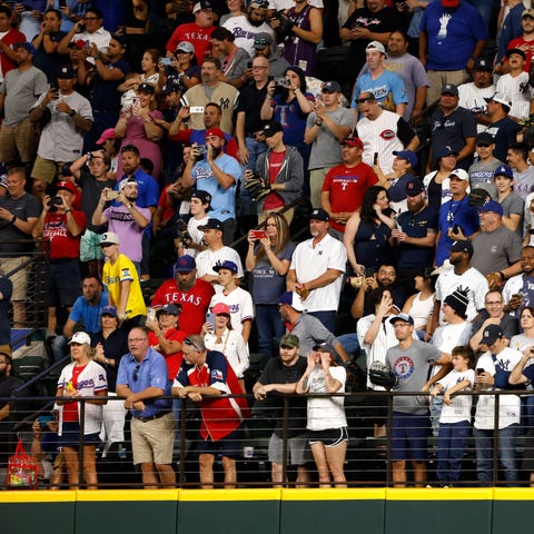 Baseball fans stand in the outfield before Aaron J