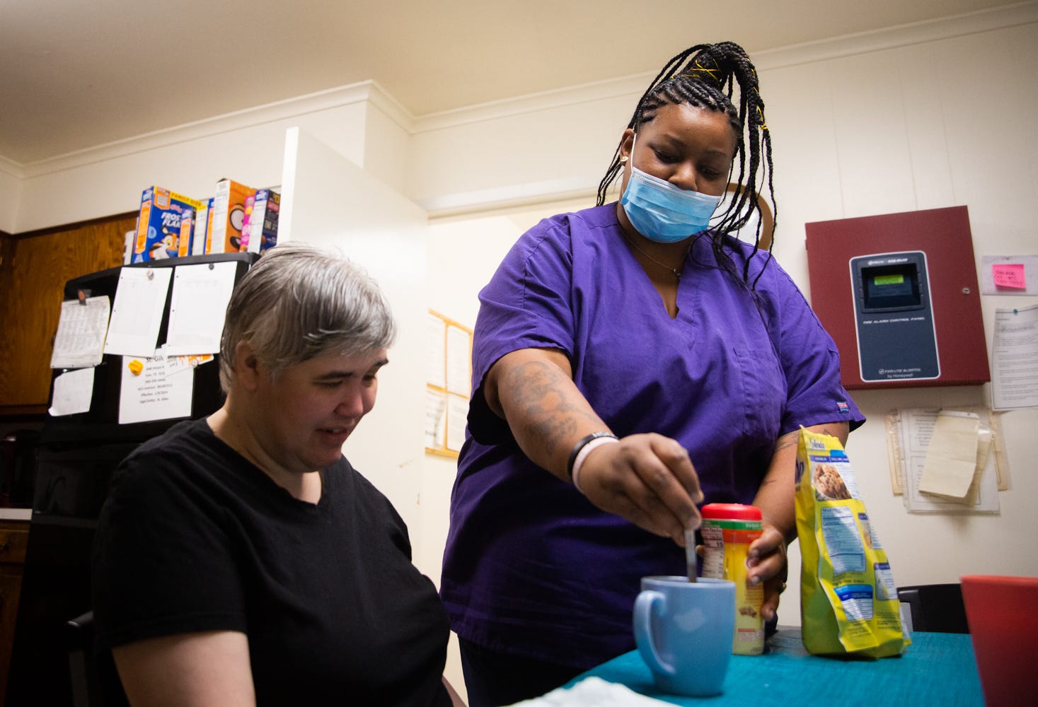 Tre'Asia Anderson helps client Cindy stir sweetener into her coffee at the Tyler group home where Anderson works for Caregiver Inc. The 33-year-old caregiver made $9 an hour this spring, and a timecard provided to the Statesman shows she had just two breaks in a 70-hour stint.