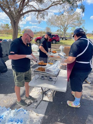 Lo chef/ristoratore di Jupiter David Schroeder (a sinistra) porge piatti di pasta per i sopravvissuti all'uragano Ian a Cape Coral.