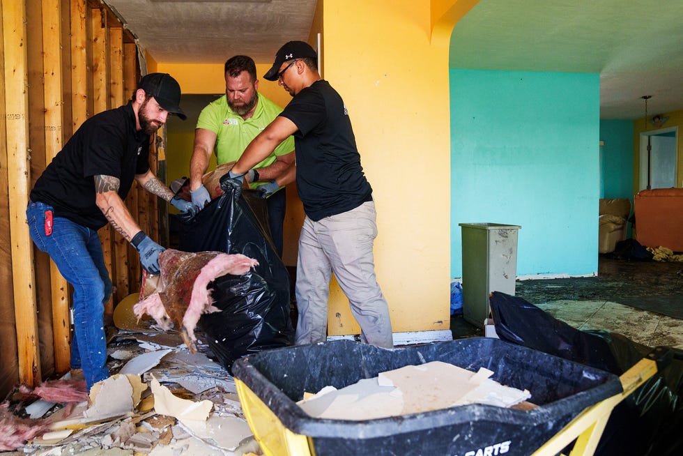 Oct 5, 2022; Fort Myers, FL, USA; Contractor Brad Zachritz, middle, begins to tear down damaged drywall and insulation in his mother Peggy's home with his employees Jacob Hedgepath, left, and Desmond Eilam. Peggy Zachritz is one of several Fort Myers area residents whose home was severely damaged by Hurricane Ian when it came ashore as a Category 4 storm..
