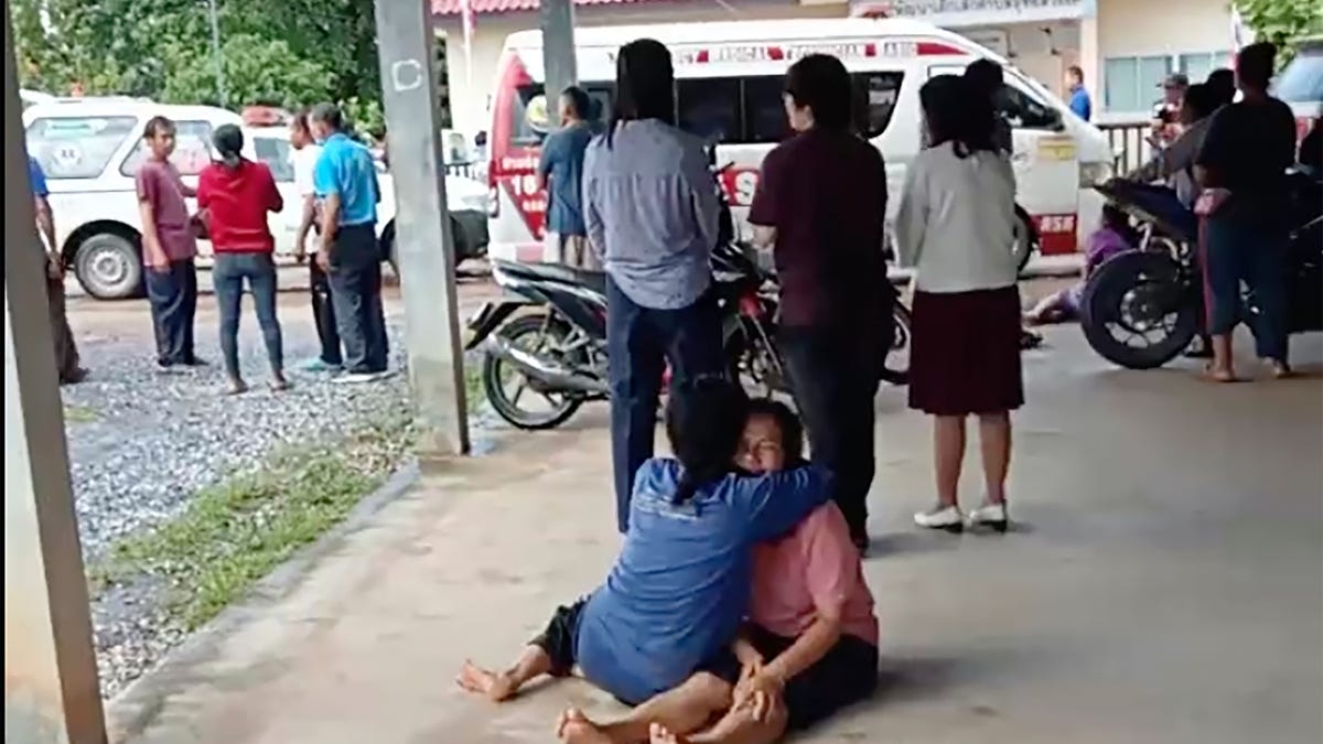 In this image taken from video, a distraught woman is comforted outside the site of an attack at a daycare canter, Thursday, Oct. 6, 2022, in the town of Nongbua Lamphu, north eastern Thailand. More than 30 people, primarily children, were killed Thursday when a gunman opened fire in the childcare center authorities said.