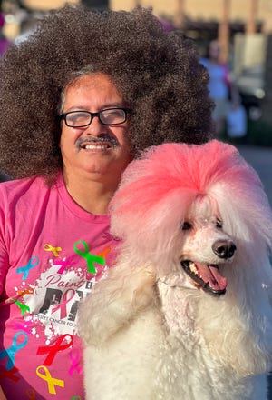 Ruben Rios เจ้าของ Creative Dog Grooming ในปาล์มดีเซิร์ท โพสท่ากับ Juanita พุดเดิ้ลที่มีขนเป็นสีชมพูเพื่อการตระหนักรู้เกี่ยวกับโรคมะเร็ง ที่งาน Paint El Paseo Pink ในปาล์มดีเซิร์ท รัฐแคลิฟอร์เนีย เมื่อวันที่ 8 ต.ค. 2022