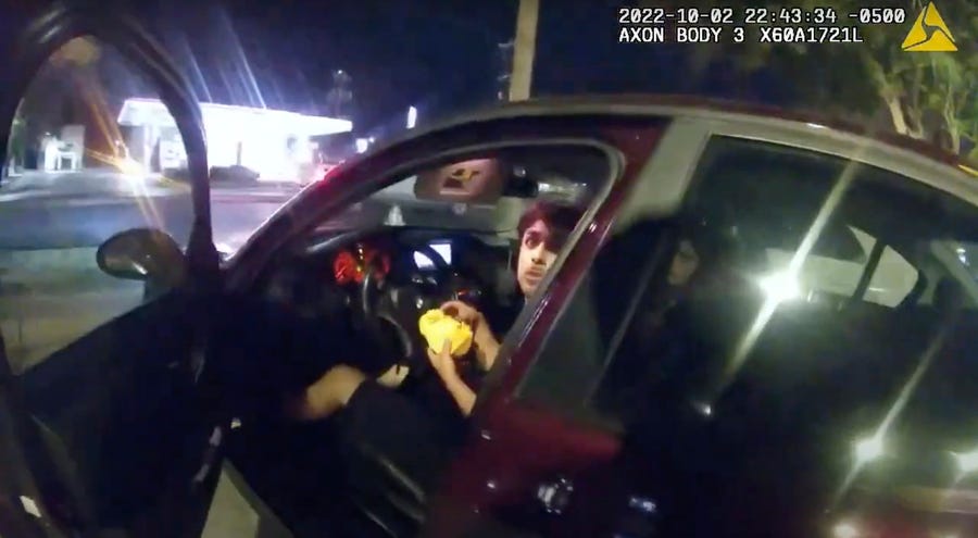 In this image taken from Oct. 2, 2022 police body camera video and released by San Antonio Police Department, Erik Cantu looks toward San Antonio Police officer James Brennand while holding a hamburger in a fast food restaurant parking lot as the officer opens the car door in San Antonio, Texas. Brennand opened fire several times wounding the unarmed teenager as he drove away. Brennand was fired after the shooting, police training commander Alyssa Campos said in a video statement released   Wednesday, Oct. 5, 2022.  (San Antonio Police Department via AP) ORG XMIT: ILKS103