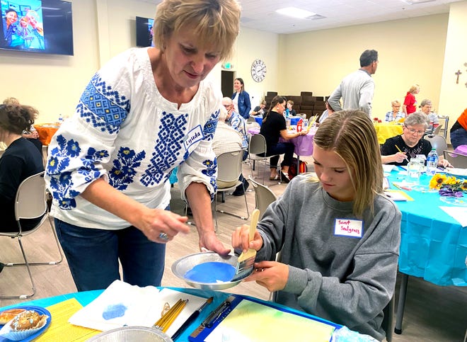 Midwest City's Luda Cameron helps 14-year-old Scout Snodgrass paint a watercolor of sunflowers. "painting for peace" A fundraiser at Kingfisher's First United Methodist Church. [Carla Hinton/The Oklahoman]