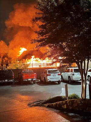 Flames from the large fire threaten vehicles parked at the neighboring hotel on the 700 block of Parkway in Gatlinburg on Sunday, Oct. 9. Cafe 420 and Gifts of Gatlinburg were among the businesses destroyed in the fire.
