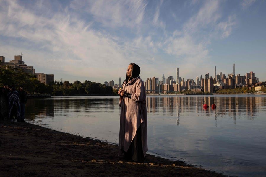 A woman prays while holding a container of water brought from Puerto Rico during an Indigenous Peoples' Day sunrise ceremony on Randall's Island in New York City on October 10, 2022. - The federal holiday to mark Columbus Day is also officially recognized as Indigenous Peoples' Day, following a proclamation by US President Joe Biden.