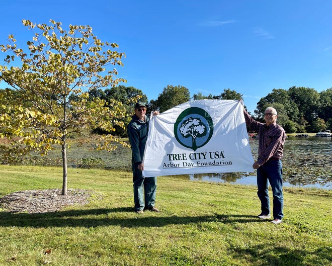 Richard Eckert poses for a photograph next to one of the newest trees at Baw Beese Lake with Hillsdale City Forester Gary Stachowicz.
