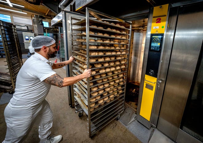 An employee pushes bread rolls into one of the gas heated ovens in the producing facility in Cafe Ernst in Neu Isenburg, Germany, Monday, Sept. 19, 2022. Andreas Schmitt, head of the local bakers' guild, said some small bakeries are contemplating giving up due to the energy crisis.