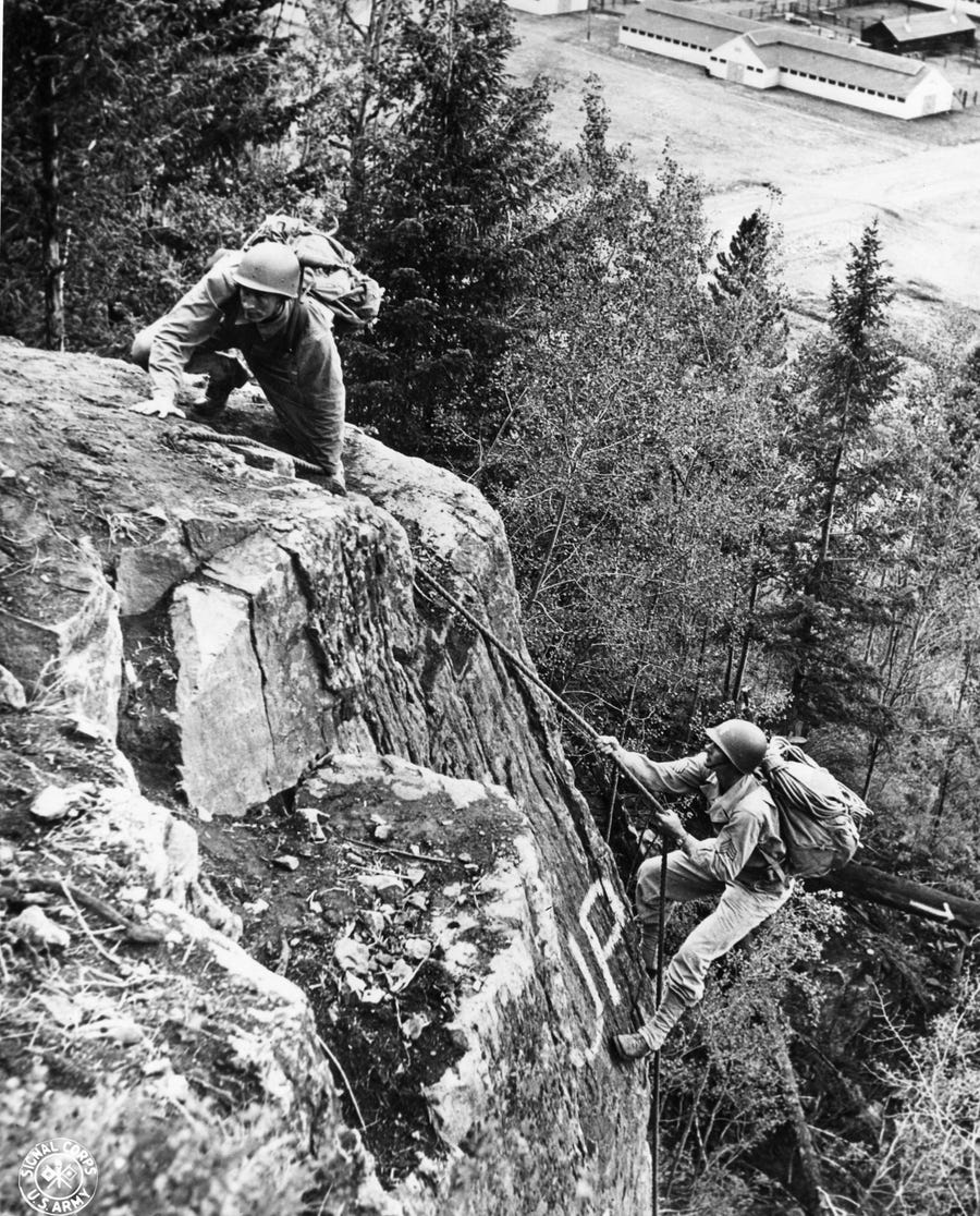 Soldiers scale a rock outcropping during training on the Mountain Obstacle Course at Camp Hale in this 1943 photograph taken by the U.S. Army Signal Corps.