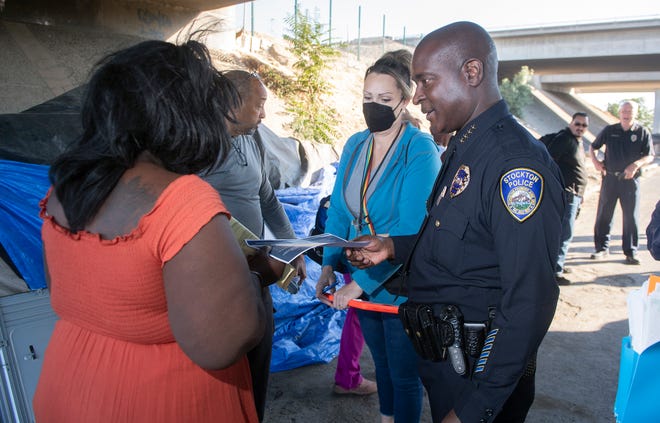 Stockton Chief of Police Stanley McFadden, right, gives safety information to a homeless woman at an encampment on Church Street in downtown Stockton. 