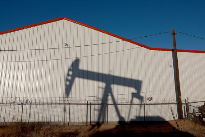 An oil pumpjack casts a shadow on a wall as it pulls oil from the Permian Basin oil field on March 14, 2022.