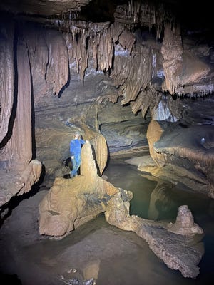 Parker Gibbons stands alongside a stalagmite in Worley’s Cave, Bluff City, Tennessee, where cave salamanders live. [Photo courtesy Rian Burris]
