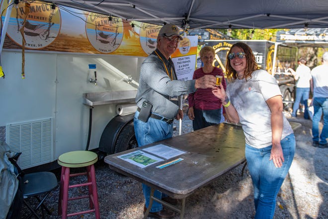 Jim Ware of the Hebron Lions Club serves ale to Chelsea Taylor of Hebron while volunteering at the Crooked Hammock stand set up at the Good Beer Festival held at Pemberton Historical Park on Saturday, Oct. 15, 2022.
