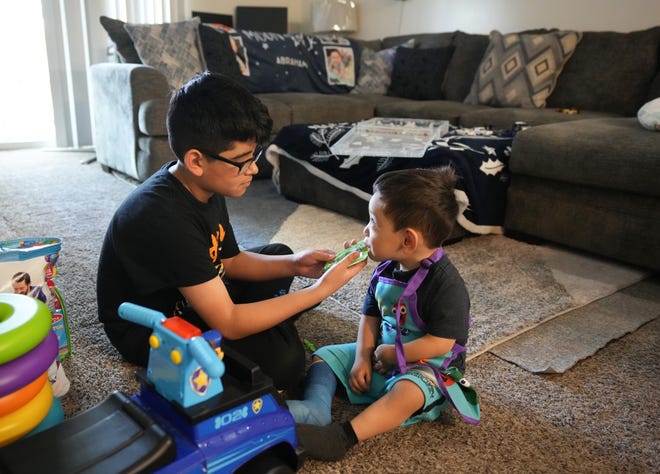 Ten-year-old Anthony Romero helps his two-year-old brother Amari with snacks at his apartment. The family can't use the living room right now due to a Christmas Eve flood from a burst pipe. Families need towels, sheets and furniture to replace damaged items. Amari, who has a speech delay, still needs his iPad to help him communicate.