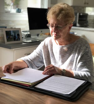 Claire Auger is seen here at her dining room table Friday, October 7, 2022 as we read through the written history of St. Thomas' School in Sanford, Maine. Auger has been a volunteer at the school since it opened 50 years ago.