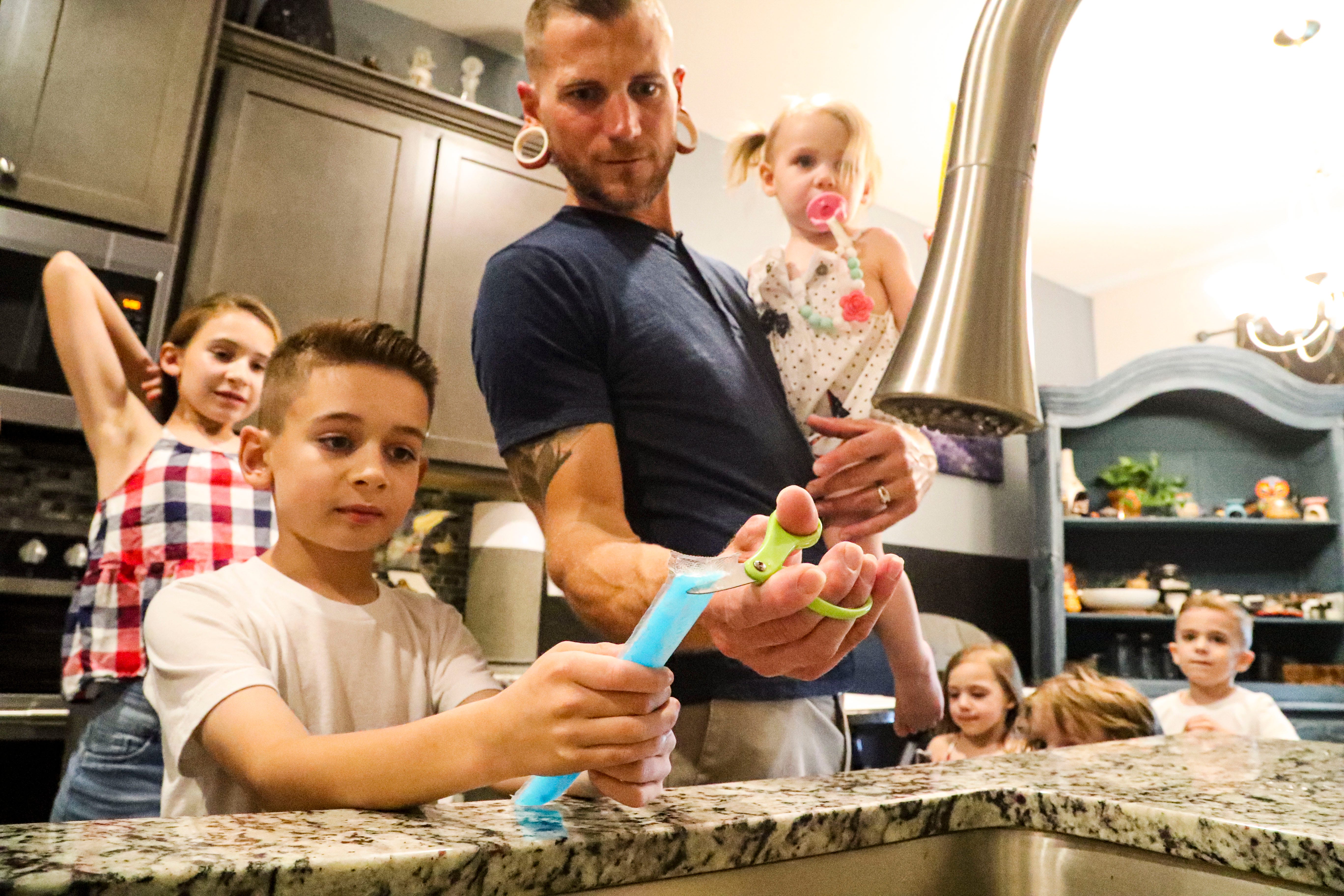 Kurt opens a popsicle for Nathaniel. Erin and Kurt Zeigler and their 6 children; Maddison, 11, Nathaniel, 8, Aaron, 5, Freya, 3, Sebastian, 2, Airis, 1. They live in a new construction home in Fort Myers that their landlords are now raising their rent by overt $1,000. They are looking for a new place to live, but that his hard with such a large family.