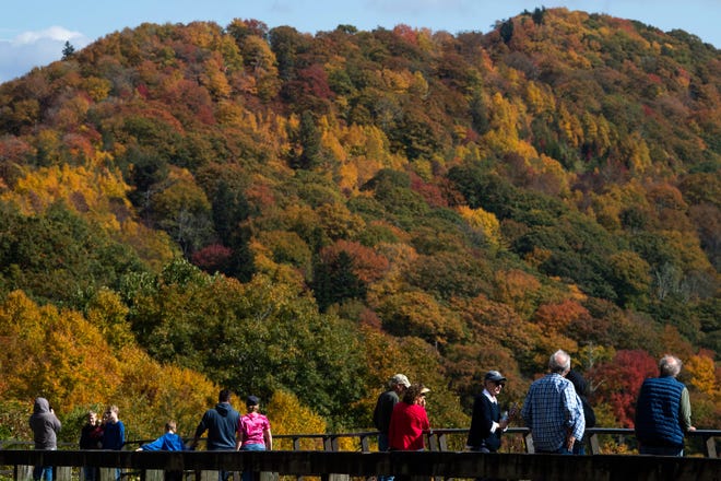 Tourists view the fall foliage from the Swinging Bridge Quiet Walkway trailhead in the Great Smoky Mountains National Park on Oct. 11, 2022.